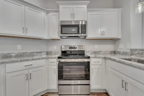 a kitchen with granite countertop white cabinets and a stove