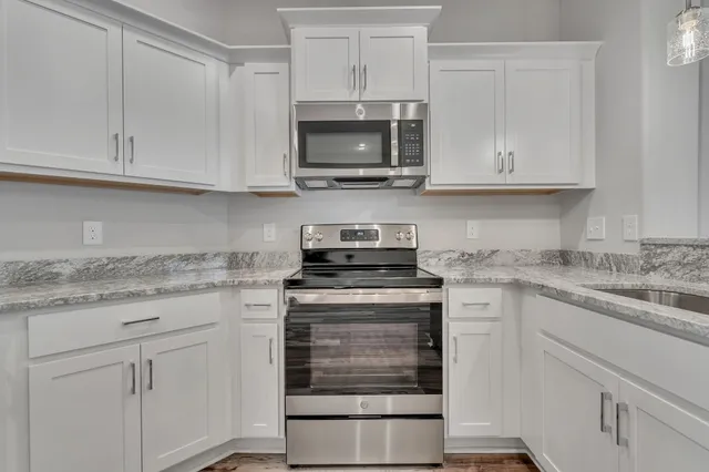 a kitchen with granite countertop white cabinets and a stove