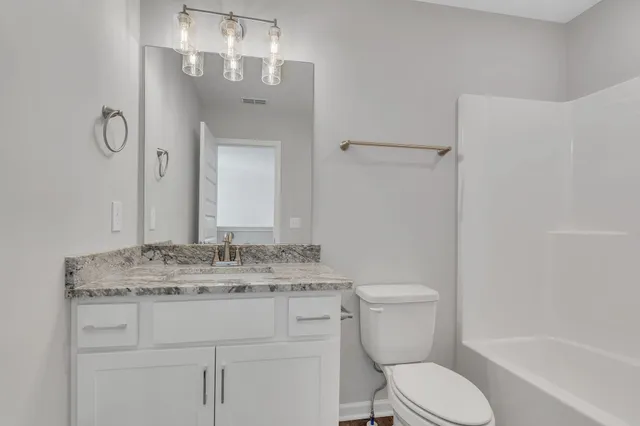 a bathroom with a granite countertop toilet sink and mirror