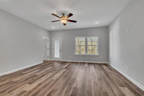 a view of an empty room with a window and wooden floor