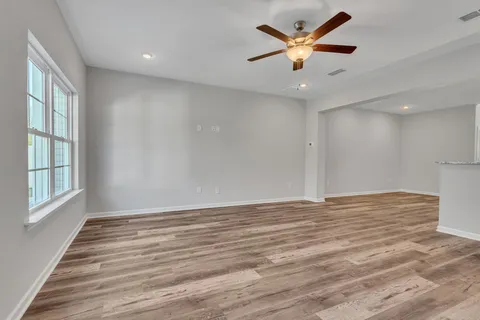 a view of an empty room with window and a chandelier fan