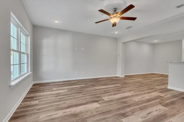 a view of an empty room with window and a chandelier fan