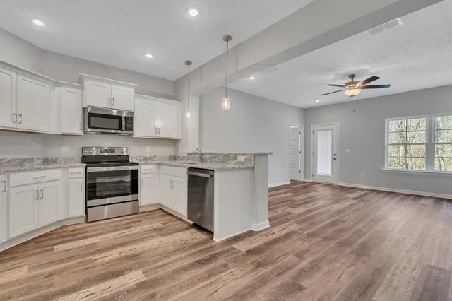 a kitchen with granite countertop a stove cabinets and a wooden floor
