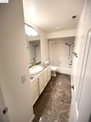 a bathroom with a granite countertop sink and mirror with bathtub