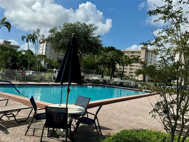 a view of a swimming pool with a patio and a yard