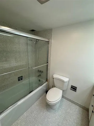 a white toilet sitting next to a shower