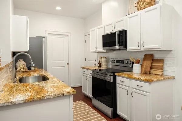 a kitchen with stainless steel appliances granite countertop a sink stove and microwave