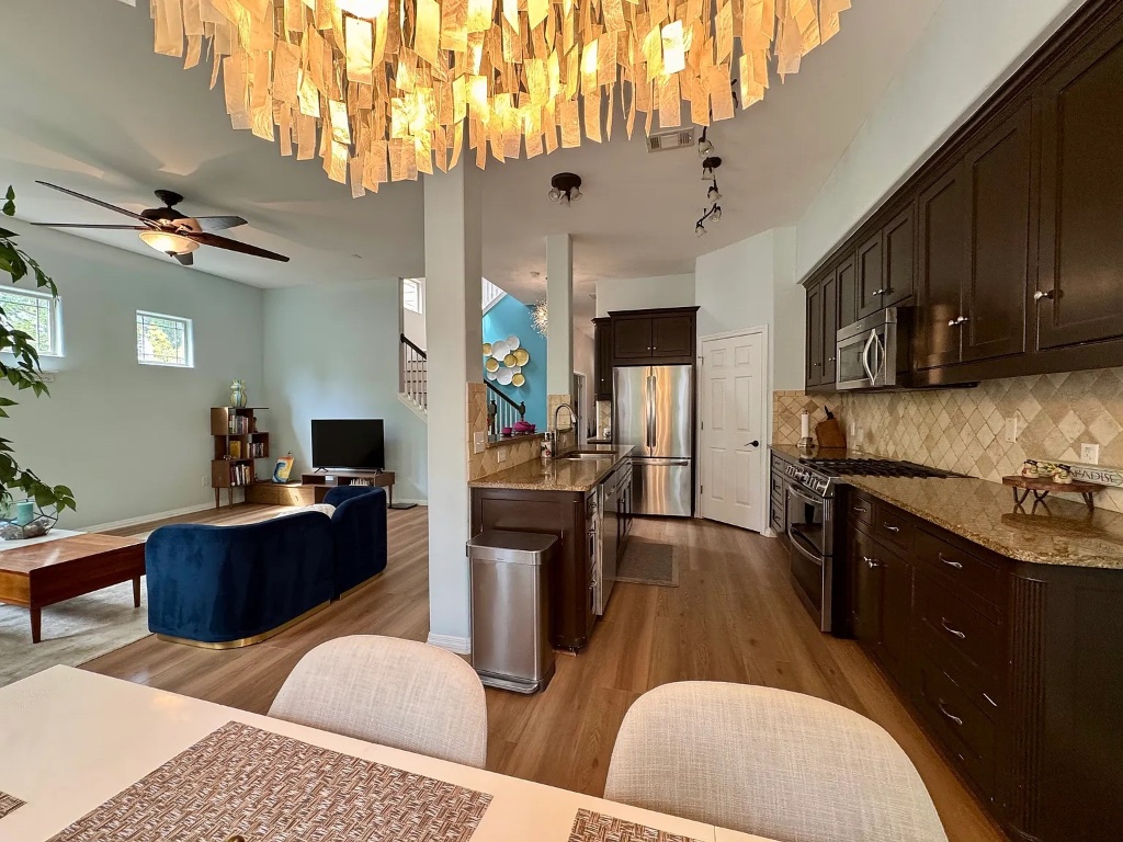 1009 Taulbee Lane, Unit H Austin, TX 78757 - Photo 17 of 17 a kitchen with stainless steel appliances kitchen island granite countertop a refrigerator a stove a sink dishwasher and white cabinets with wooden floor
