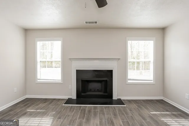 an empty room with windows and fireplace