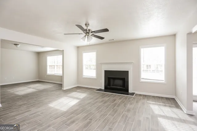 an empty room with windows fireplace and wooden floor