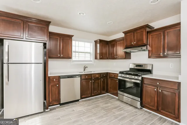 a kitchen with stainless steel appliances granite countertop a refrigerator stove a sink and a granite counter tops