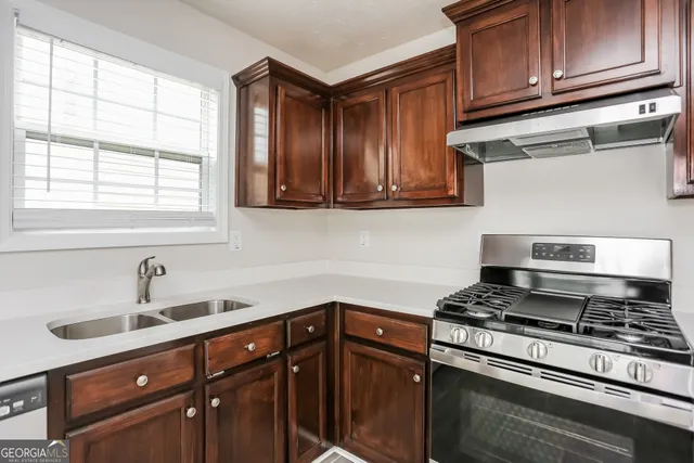 a kitchen with stainless steel appliances granite countertop a sink stove and cabinets
