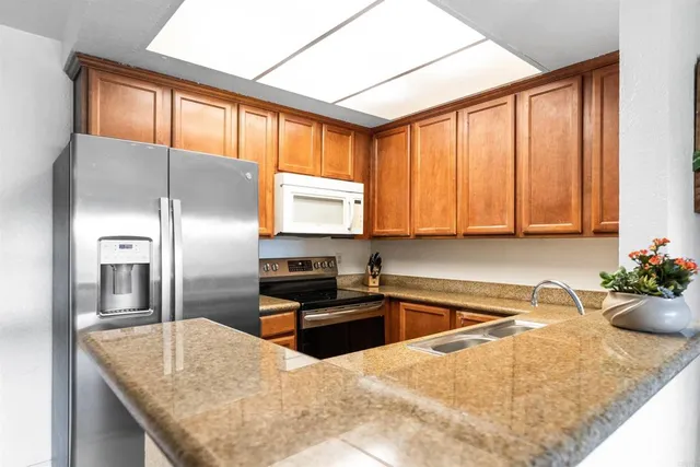 a kitchen with stainless steel appliances granite countertop a sink refrigerator and microwave