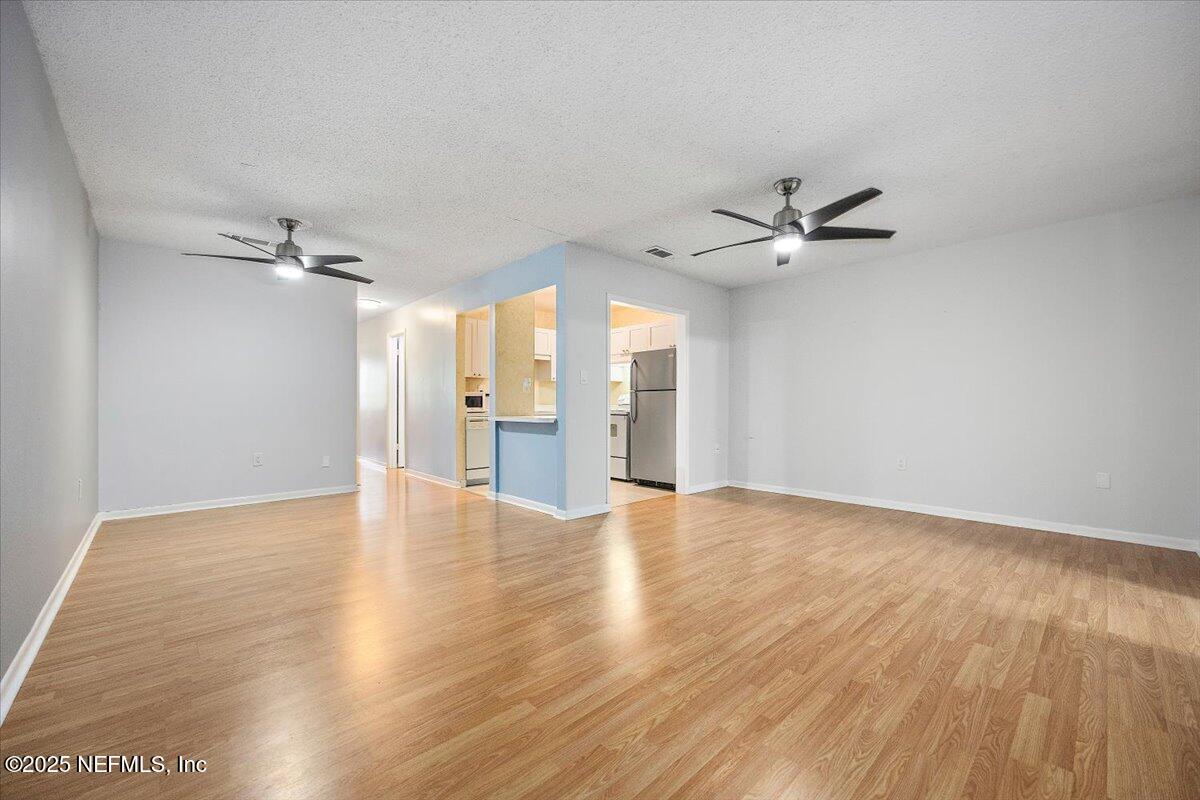 2628 Southwest 14th Drive, Unit 326 Gainesville, FL 32608 - Photo 4 of 17 a view of an empty room with a ceiling fan and wooden floor