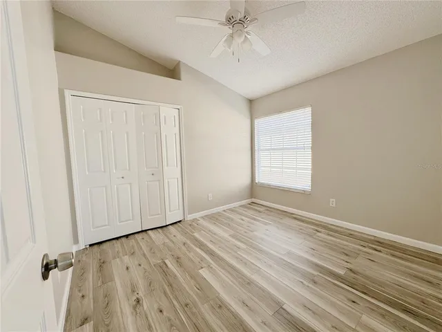 an empty room with wooden floor fan and windows