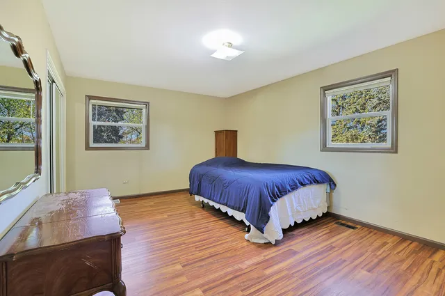 a spacious bedroom with a bed and wooden floor