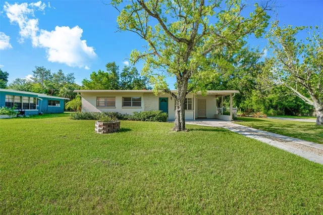 a view of house with a big yard and large trees