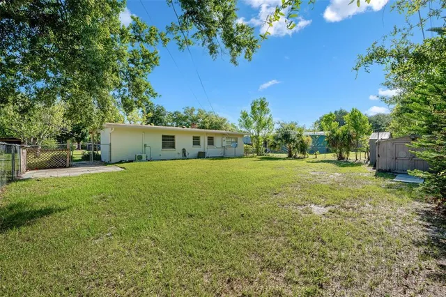 a view of a house with backyard and trees
