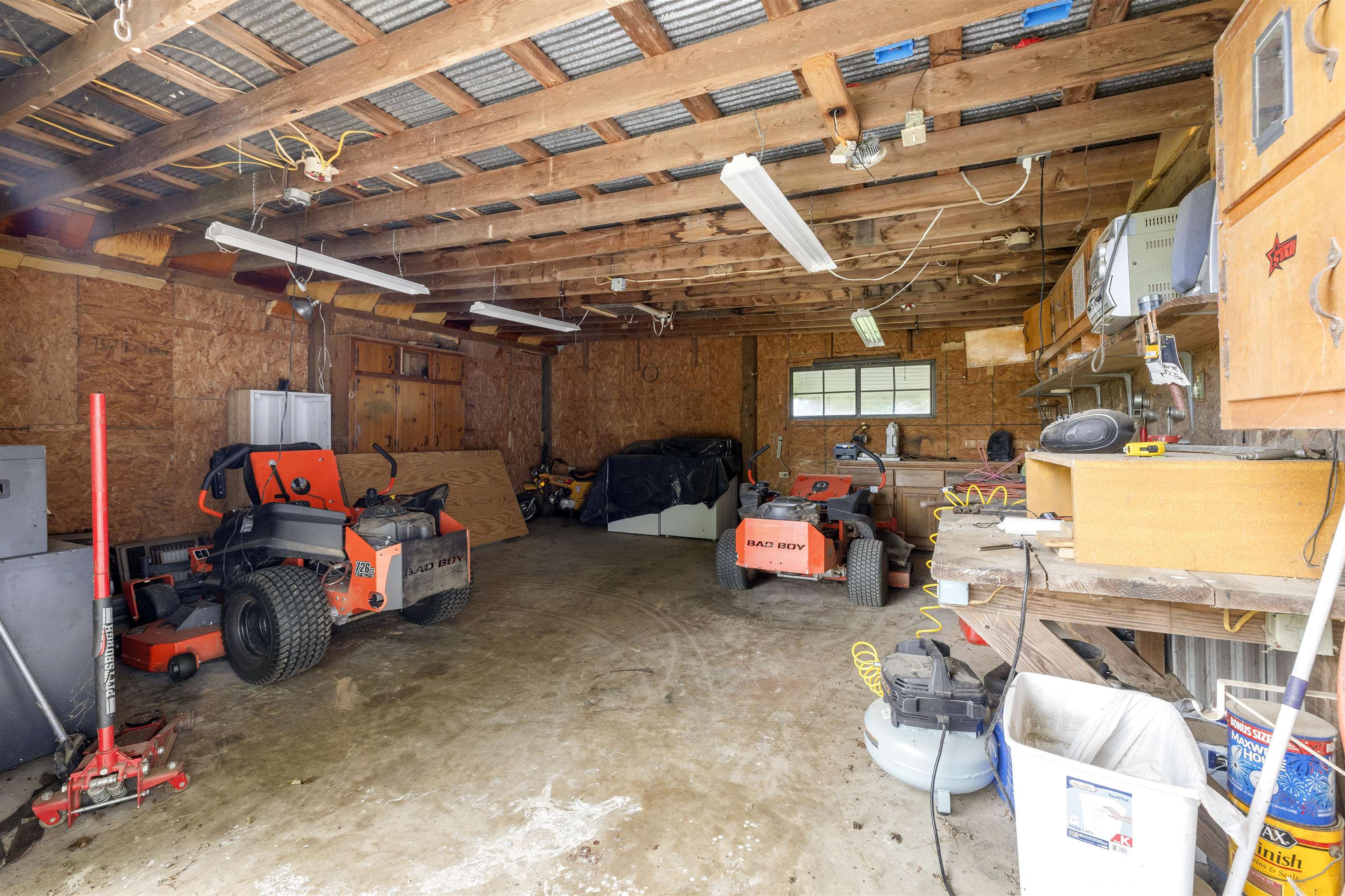 2665 Powell Chapel Road Middleton, TN 38052 - Photo 31 of 36 Spacious workshop with concrete flooring, exposed wood beam ceiling, fluorescent lighting, built-in wooden shelving, and a single pane window
