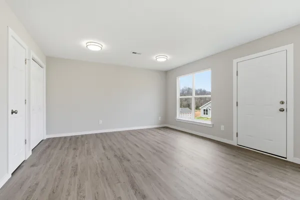 an empty room with wooden floor and a window