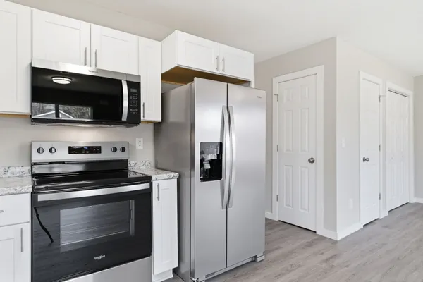 a kitchen with granite countertop white cabinets and appliances