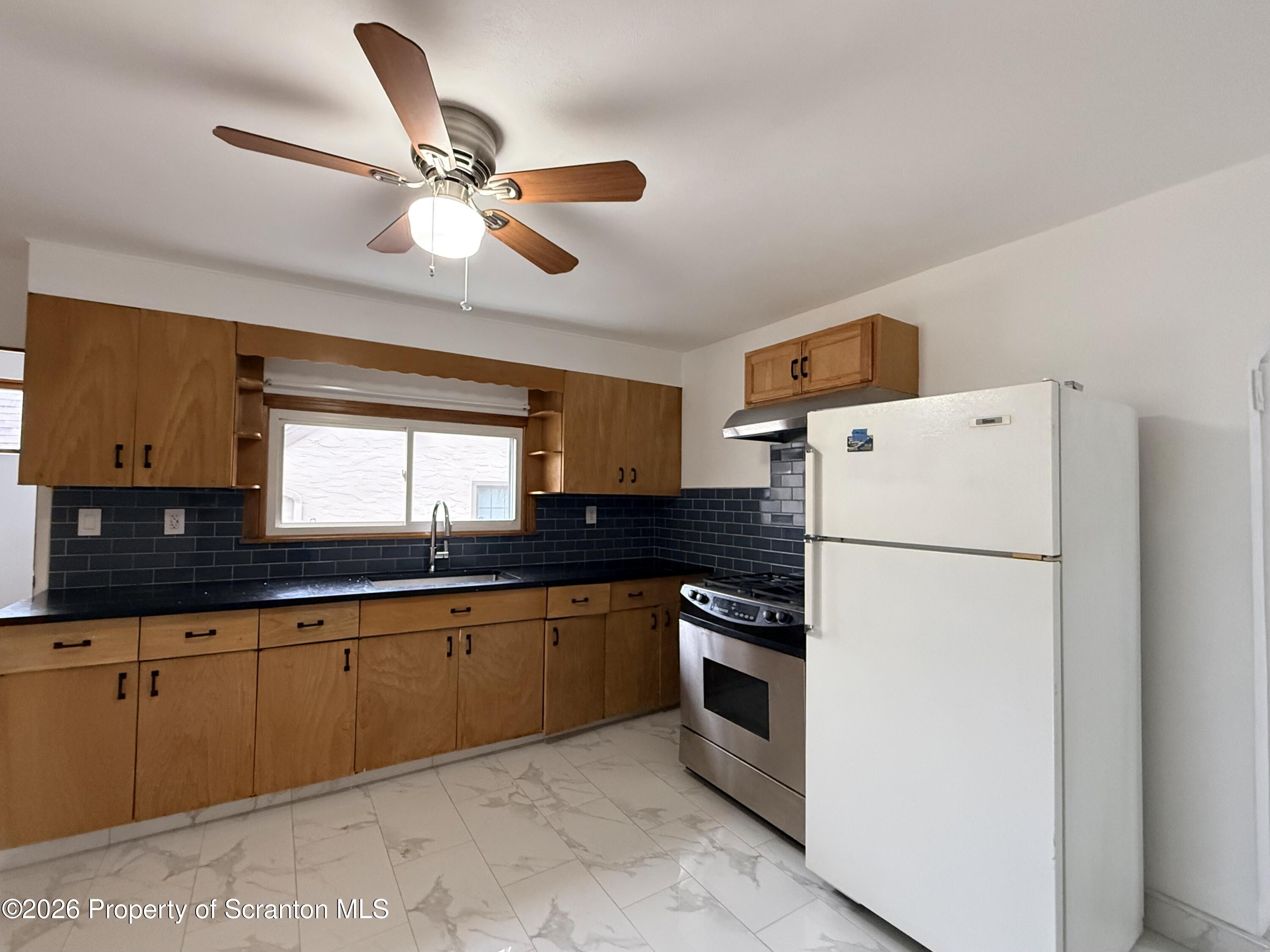 1717 Clay Avenue, Unit 2 Scranton, PA 18509 - Photo 2 of 5 a kitchen with granite countertop a refrigerator a sink a stove and white cabinets