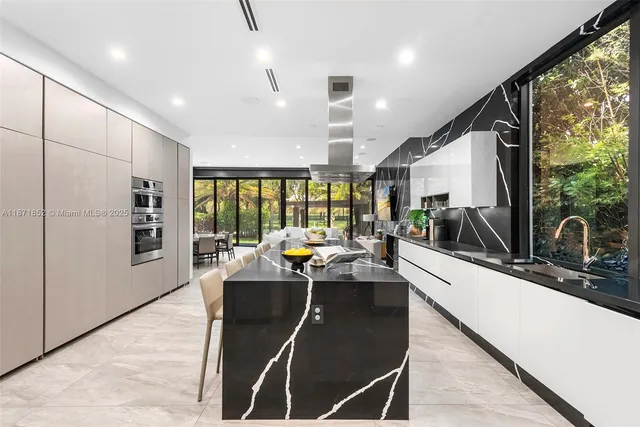 a living room with stainless steel appliances furniture a large window and a wooden floor
