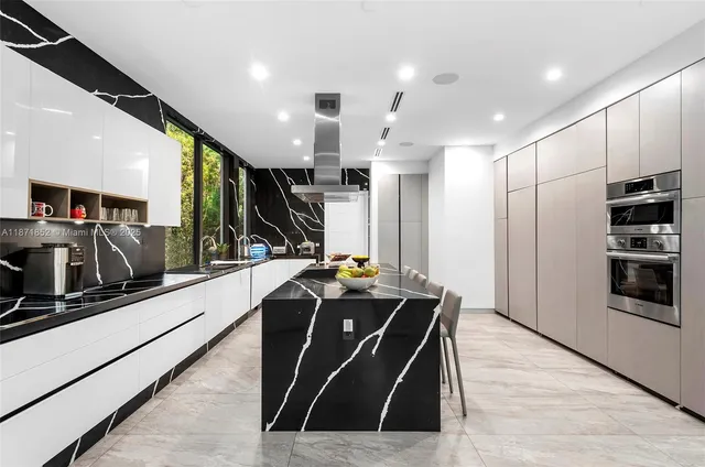 a kitchen with stainless steel appliances kitchen island granite countertop a refrigerator a stove and a sink with wooden floor