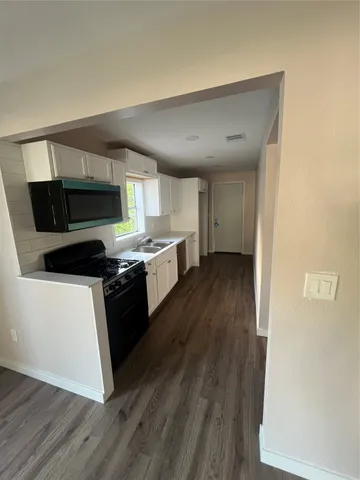 a kitchen with granite countertop a stove top oven a sink dishwasher and a refrigerator with wooden floor