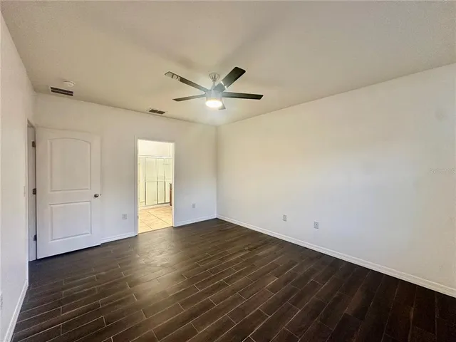 an empty room with wooden floor and ceiling fan