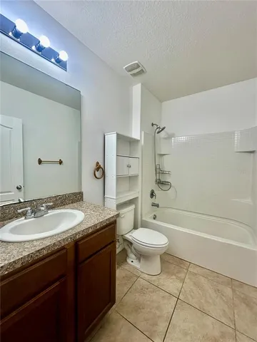 a bathroom with a granite countertop sink a toilet a mirror and bathtub