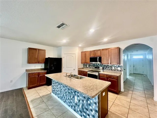 a large kitchen with kitchen island a sink stove and refrigerator