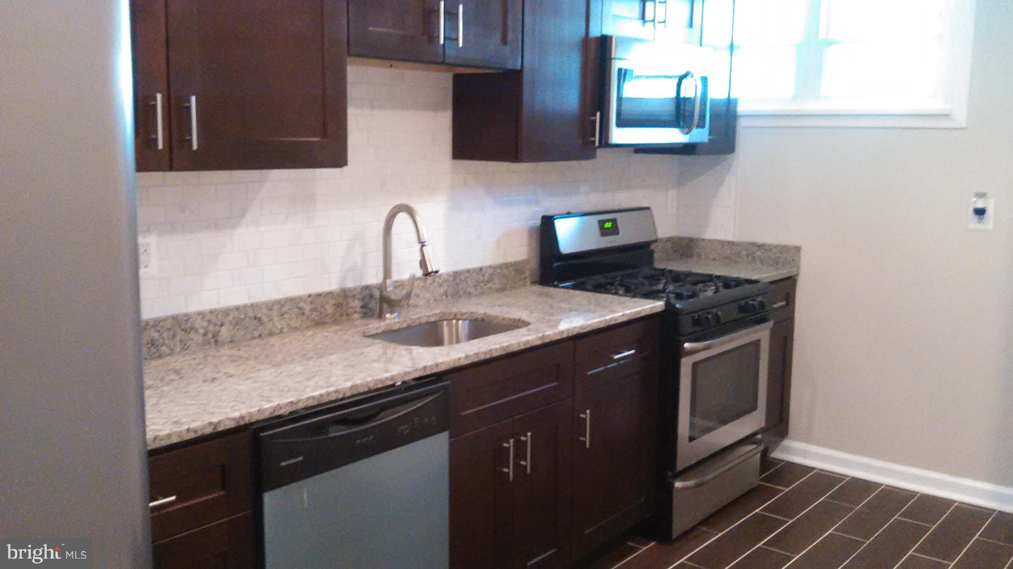 7701 Greenleaf Road Landover, MD 20785 - Photo 7 of 24 a kitchen with stainless steel appliances granite countertop a sink stove and cabinets
