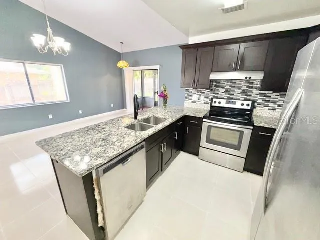a kitchen with stainless steel appliances granite countertop a sink stove and refrigerator