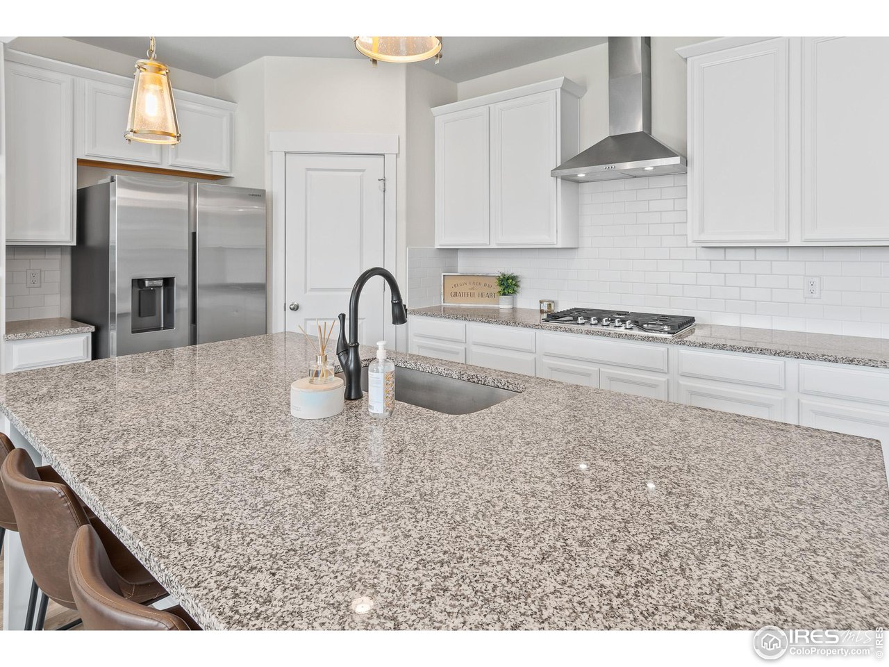 2107 Setting Sun Drive Windsor, CO 80550 - Photo 25 of 40 a kitchen with stainless steel appliances granite countertop a sink a stove and white cabinets
