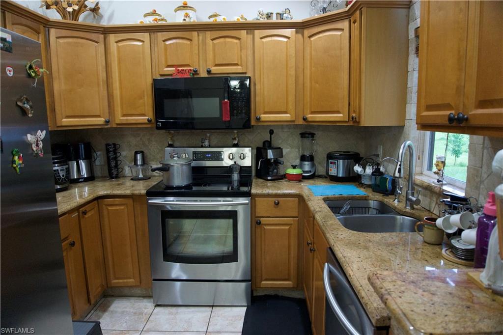 2407 Randall Boulevard Naples, FL 34120 - Photo 28 of 46 a kitchen with stainless steel appliances granite countertop a sink a stove and a microwave