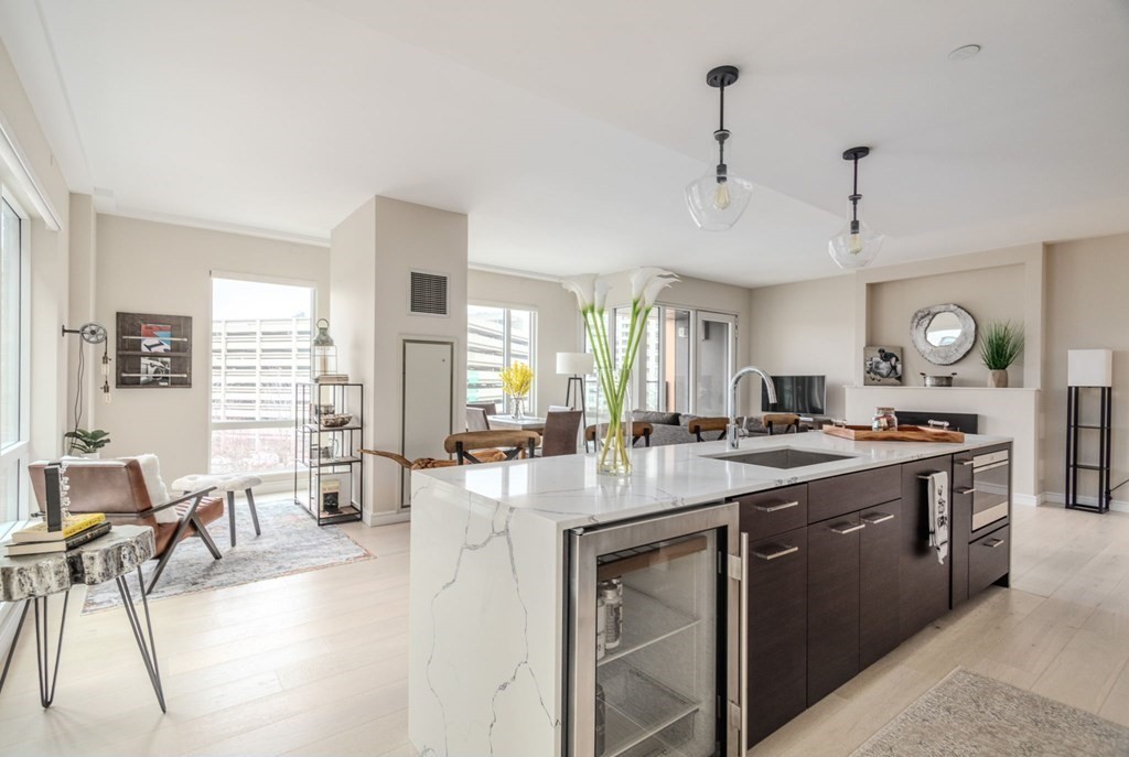 110 Broad Street, Unit 501 Boston, MA 02110 - Photo 25 of 41 a large kitchen with kitchen island a large counter space a sink appliances and living room view