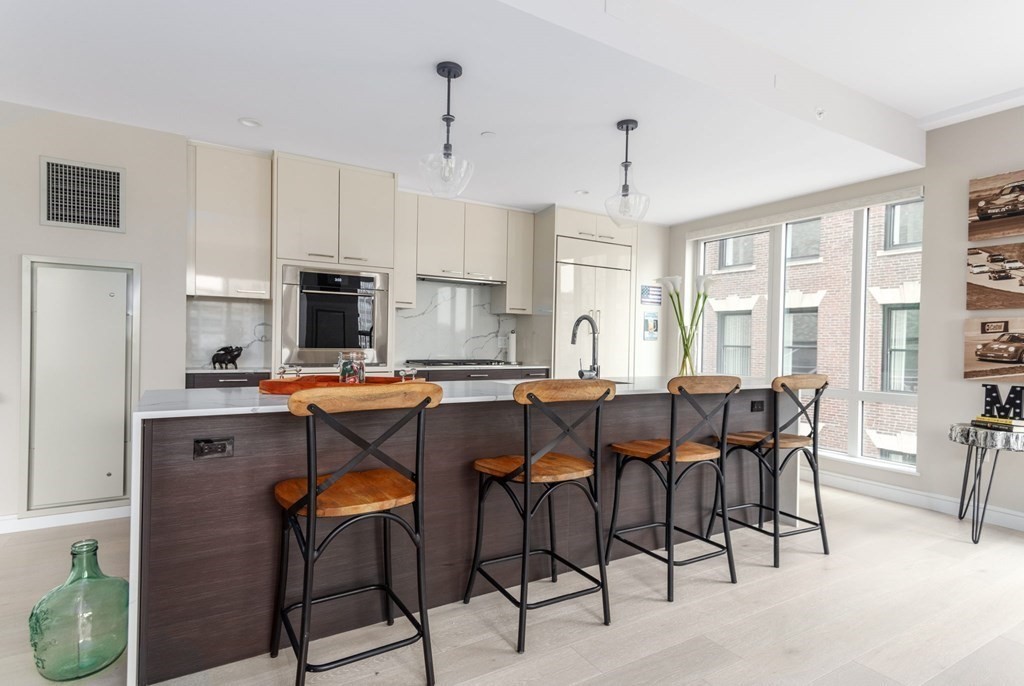 110 Broad Street, Unit 501 Boston, MA 02110 - Photo 26 of 41 a kitchen with stainless steel appliances kitchen island granite countertop a table chairs sink and cabinets