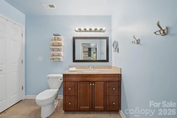 a bathroom with a granite countertop toilet sink and mirror