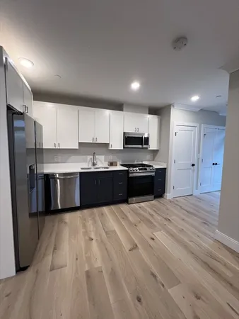 a large kitchen with stainless steel appliances granite countertop a stove a sink dishwasher a refrigerator and a oven with wooden floor