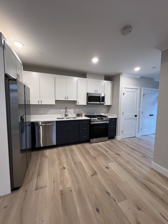 157 Everett Street, Unit 101 Boston, MA 02134 - Photo 2 of 7 a large kitchen with stainless steel appliances granite countertop a stove a sink dishwasher a refrigerator and a oven with wooden floor