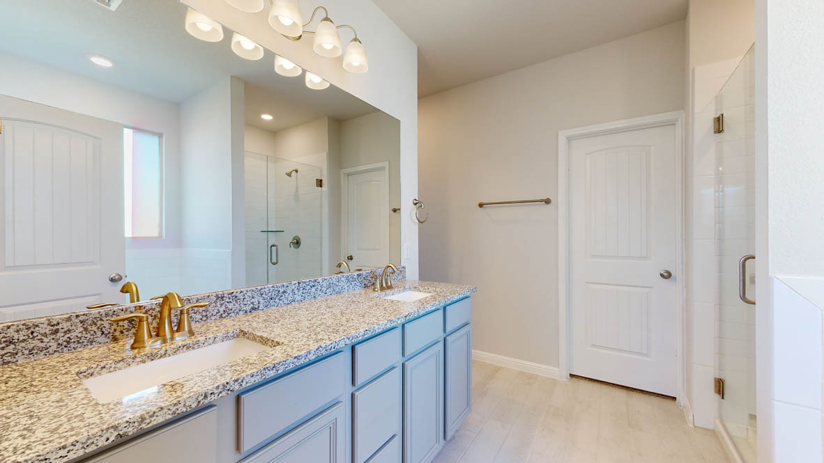 808 Gauge Road Thorndale, TX 76577 - Photo 13 of 31 A well-appointed primary bathroom features dual vanities with granite counters and a spacious glass-enclosed shower.