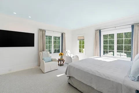 a spacious bedroom with a large bed and a flat tv screen on dresser