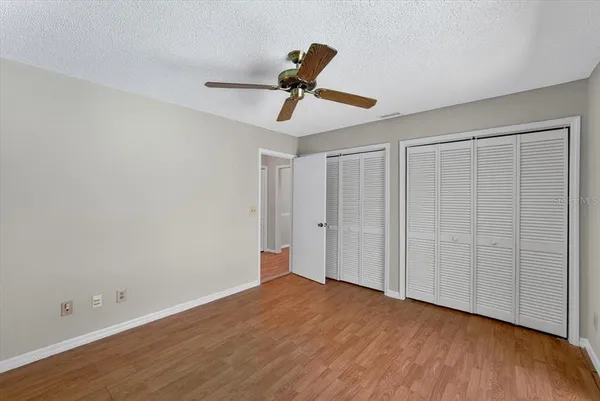 a view of empty room with wooden floor and ceiling fan
