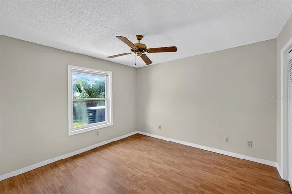 an empty room with wooden floor and ceiling fan