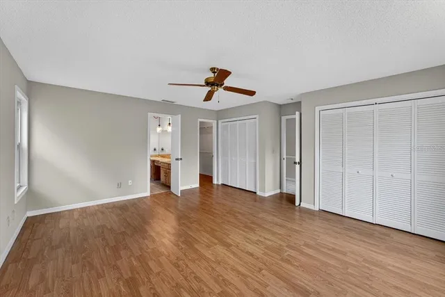 a view of empty room with wooden floor and ceiling fan