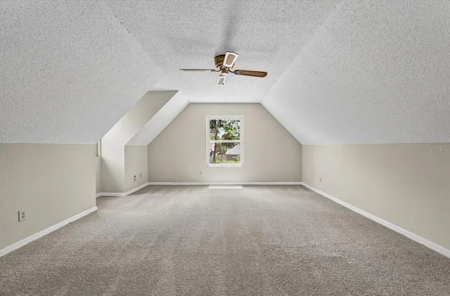 an empty room with windows and ceiling fan