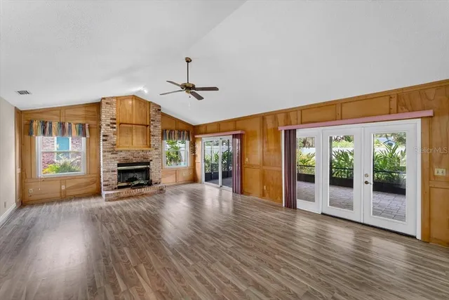 a view of an empty room with wooden floor a fireplace and a window