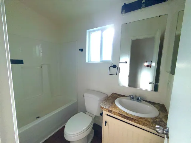 a bathroom with a granite countertop toilet sink and mirror