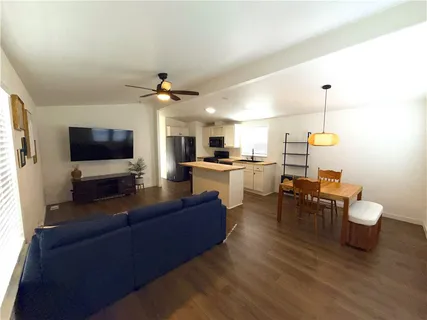 a living room with furniture a flat screen tv and kitchen view